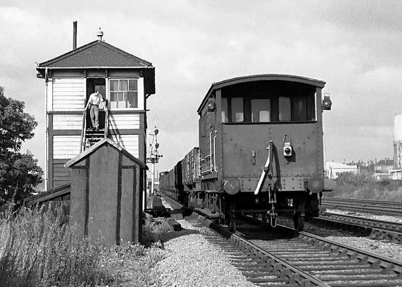 A British Railways guards van of a down freight is seen passes Queens Head Sidings Signal Box on 19th September 1964