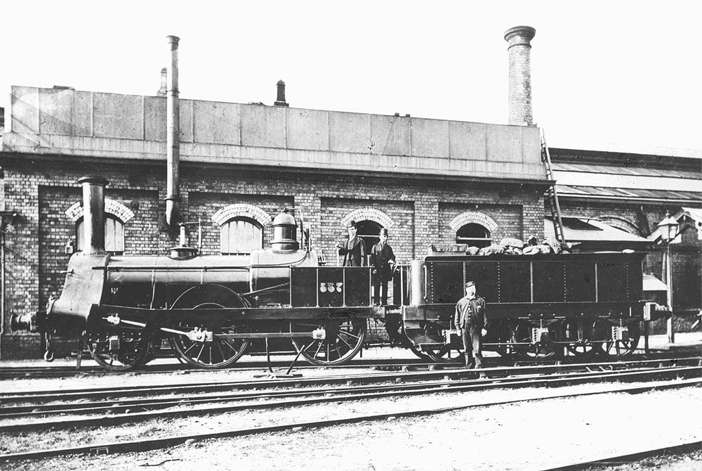 LNWR Trevithick 5ft 2-4-0 No 337 in its rebuilt form standing outside the water tank and coaling stage