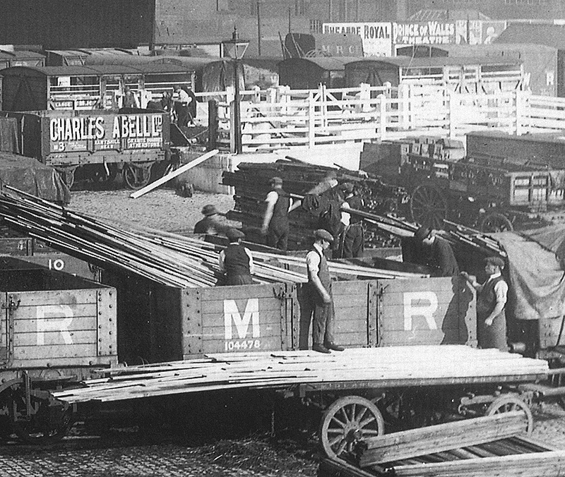 Close up showing a typical gang of yard labourers at work off-loading timber from the open wagons