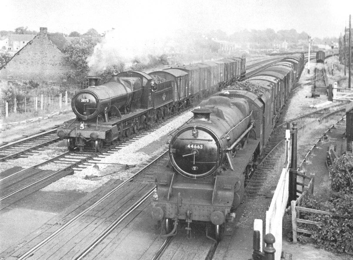 Ex-GWR 2-8-0 28xx Class No 2875 is seen on the left on a down fitted freight as it passes British Railways built 4-6-0 Class 5 No 44663 which is on a part fitted service