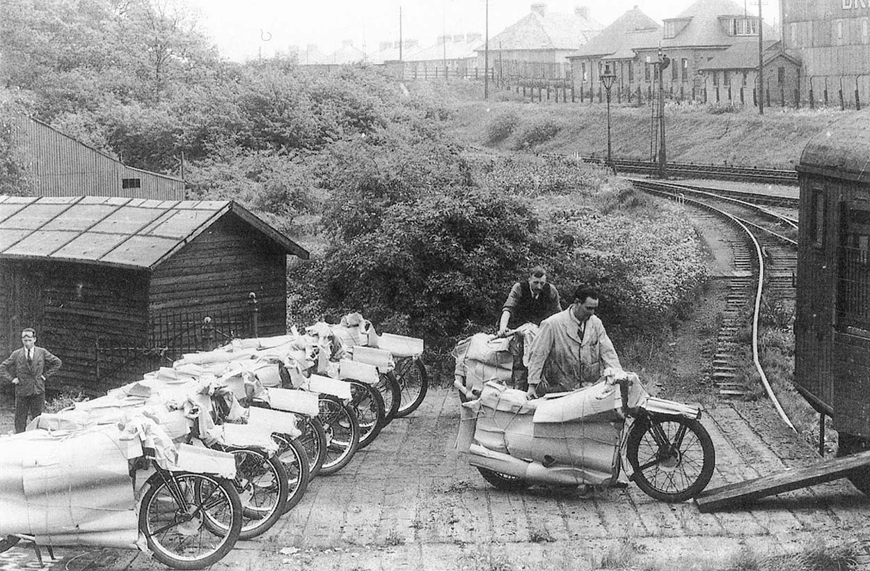 Ten carefully packaged Velocette KTT Mk3 motorcycles destined for the Isle of Man TT race are being loaded on to a carriage wagon