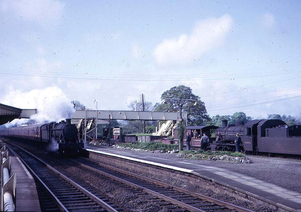An ex-Great Western Railway 4-6-0 49xx (Hall) class locomotive races through Lapworth Station on the down main line with a northbound express on Sunday 23rd May 1965
