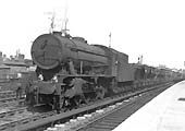 An unidentified and grimy ex-WD 'Austerity' 2-8-0 passes through the station on a down iron ore train