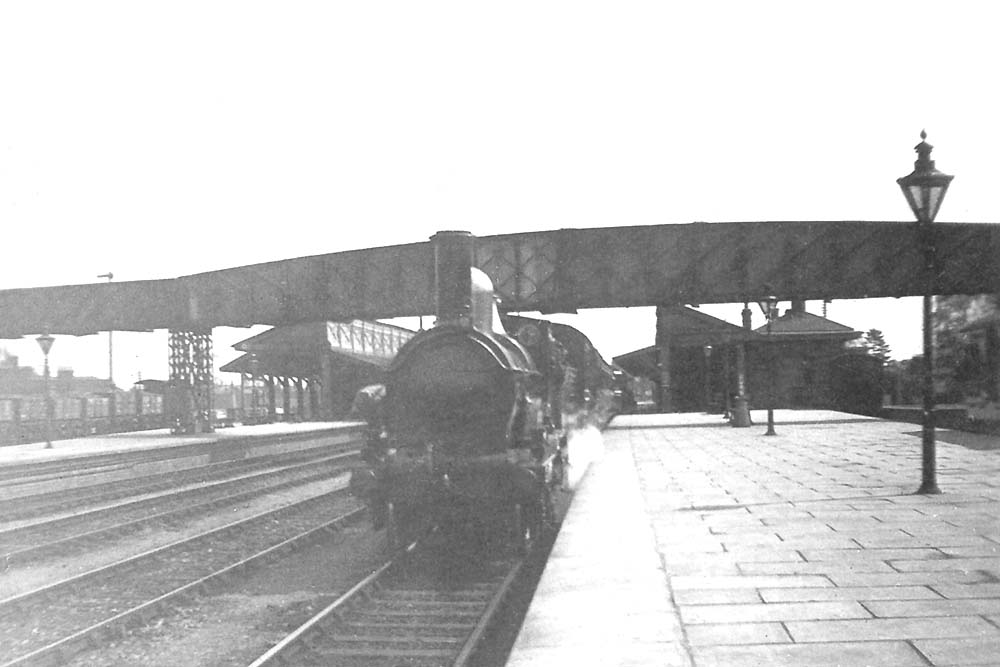 A GWR 2-4-0, possibly a '3226' class locomotive waits at the down platfor with a Birmingham bound local train