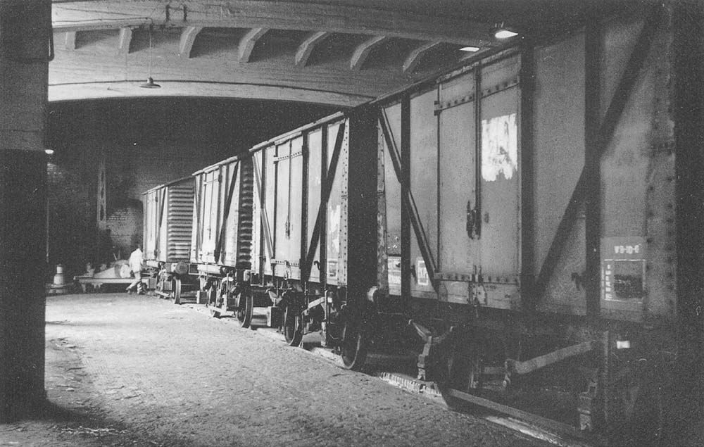 In the low level shed B a line of covered wagons are seen waiting to be unloaded
