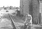View of a Mrs White as she puts out churns for water at Todenham Lane Crossing in Sept 1952
