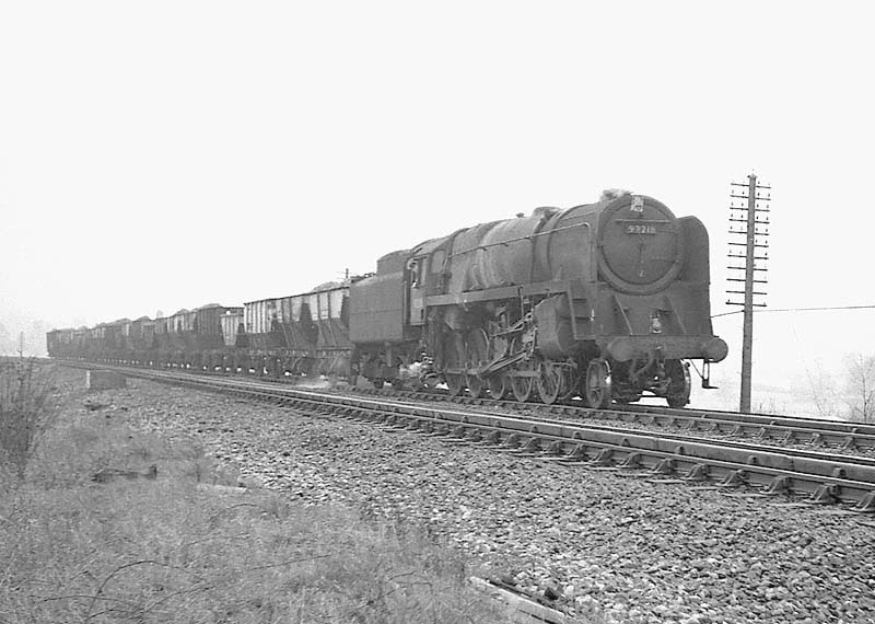 British Railways Standard Class 9 2-10-0 No 92218 is seen passing over Rowington troughs with an up through freight on 28th March 1964