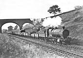 GWR 28xx Class 2-8-0 No 2879 is seen passing by Rowington trough's water tank whilst at the head of  an up goods service