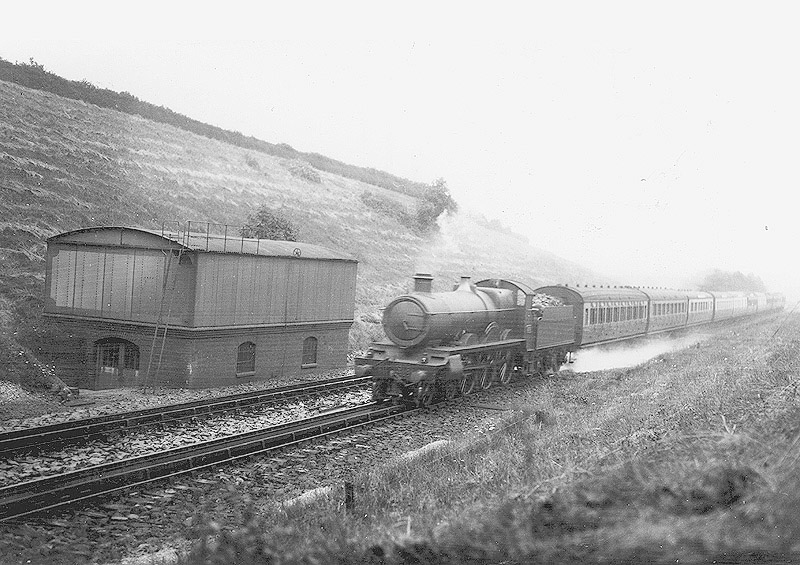 GWR 4-6-0 Saint class No 2937 'Clevedon Court' is seen a down express passing the 40,000 gallon supply tank as it picks up water at speed