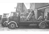 Lorries being loaded with bottled beer direct from the bottling plant's loading dock and of the barley house seen in the background