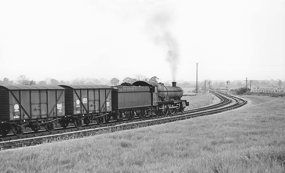 Ex-GWR 4-6-0 Hall class No 6944 'Fledborough Hall' is seen with train of empty banana vans on the connecting spur from the SMJ to GWR line on 23rd May 1964