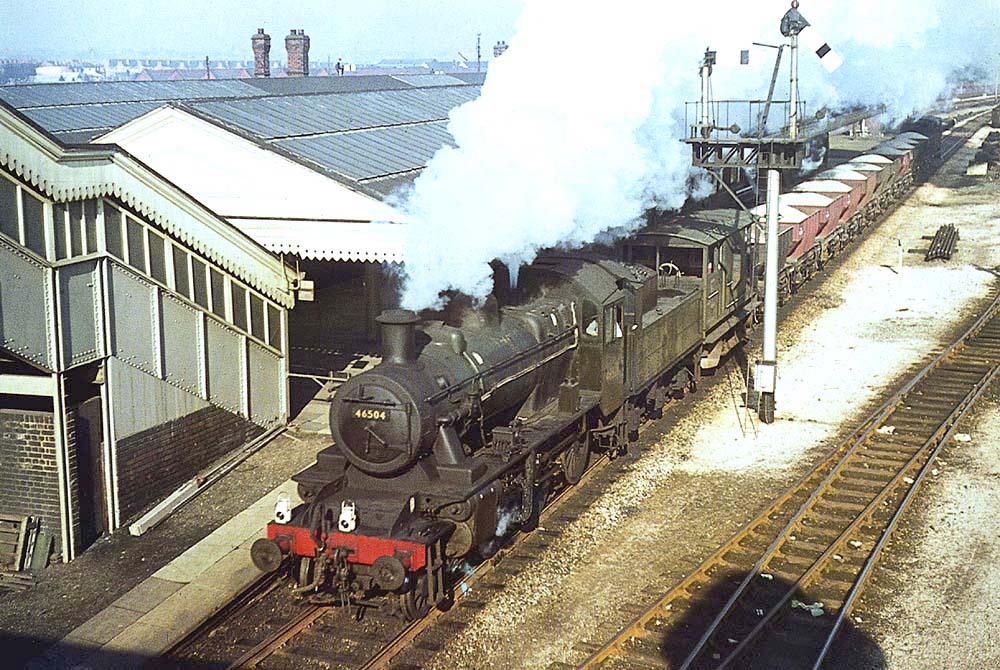British Railways built 2-6-0 No 46504 is seen wearing Brunswick Green livery whilst it passes through the up main platform on an engineer's train carrying ballast