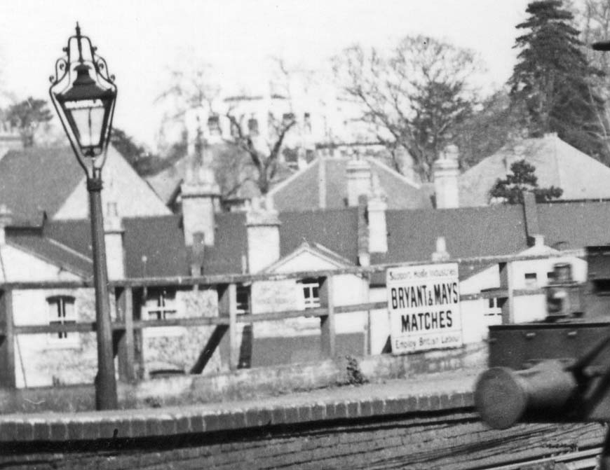 Close up showing one of Warwick station's ornate gas lampposts and to its right, an enamel Bryant & May advert