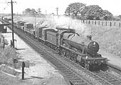 Ex-GWR 4-6-0 Hall class No 4905 'Barton Hall' is seen passing through Whitlock End Halt at the head of an up Class D express freight service