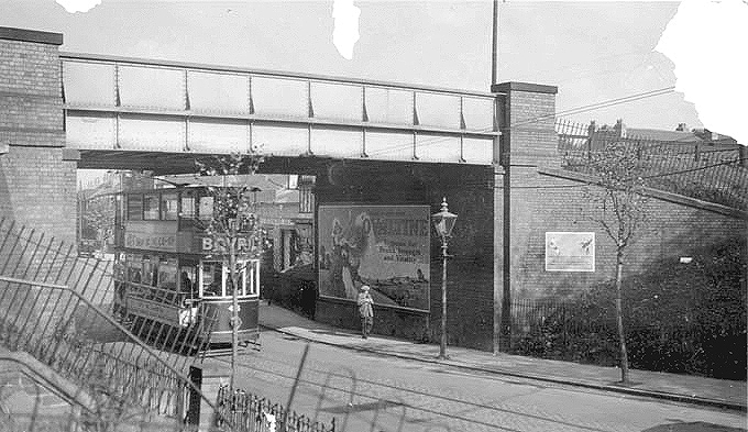 View from opposite Spencer Park's pedestrian entrance looking towards Coventry as a tram bound for Earlsdon passes under the railway bridge