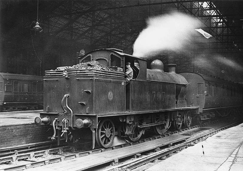 Ex-LNWR 2P 4-4-2T 'Precursor Tank' No 6797 is seen standing at the West end of Platform 2 running bunker first, whilst at the head of a local stopping train