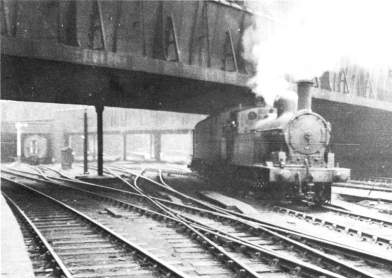 Ex-LNWR 2F 0-6-2T 'Watford Tank' No 6927 is seen waiting at the advance starting signal whilst on pilot duties with a short train of parcels vans