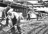 View showing the rebuilding of the station as a gang of labourers completing the backfilling of the island platform