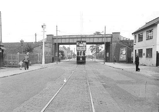 Looking along Stoney Stanton Road as a tram passes under Coventry Loop Line and in front of Bell Green goods yard which is on the left on 20th August 1939