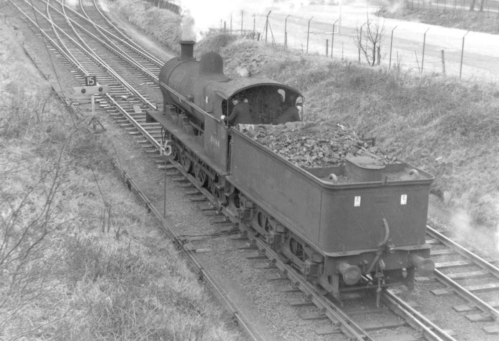 Ex-LNWR 7F 0-8-0 G2a class No 49164 is seen travelling on the down line and about to cross over on the loop line to Three Spires junction