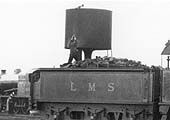 Close up showing the fireman operating the lever of the parachute water tank after having coaled the locomotive