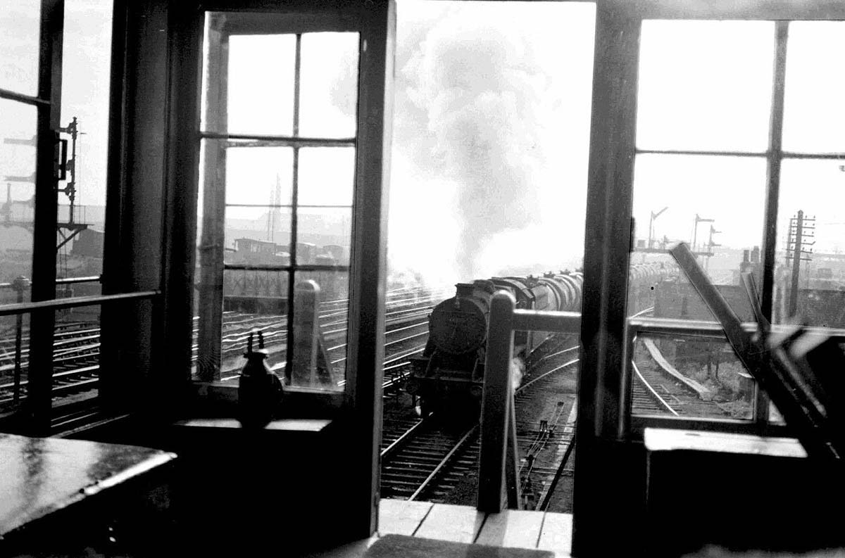 An ex-LMS 8F 2-8-0 locomotive is seen passing Rugby No 7 Signal Cabin on a Type 5 down express freight service
