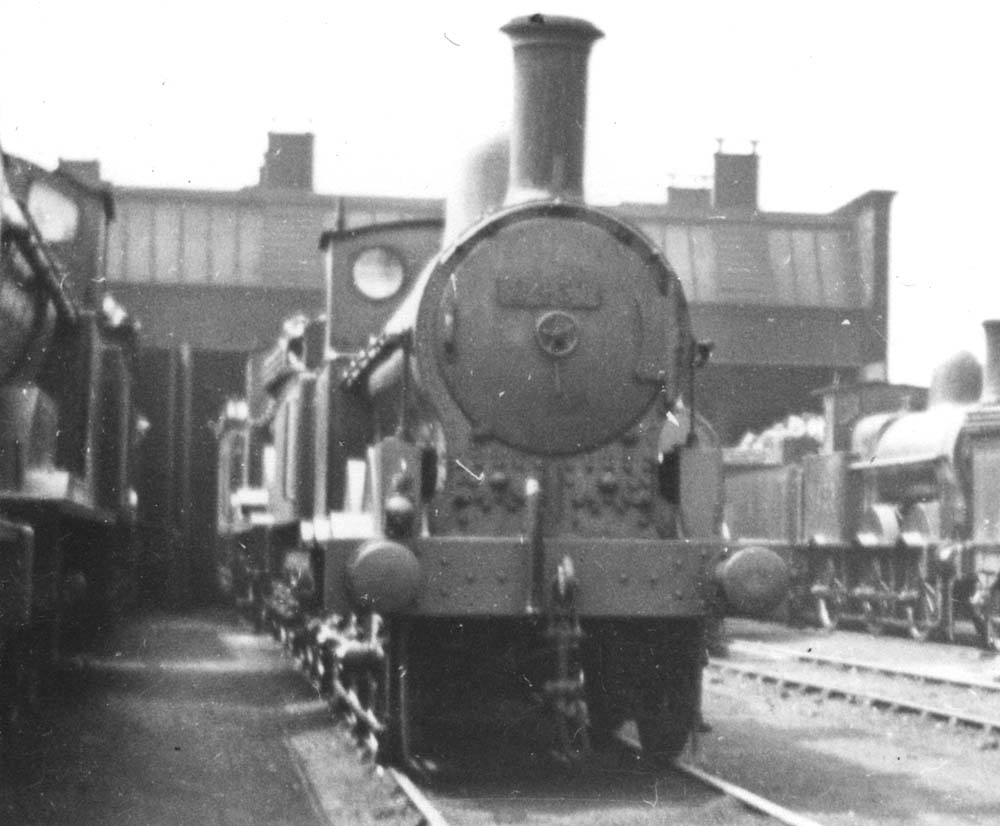 Close up of an unidentified ex-LNWR 2F 0-6-0 'Cauliflower' standing in front of and alongside of other locomotives of the same class