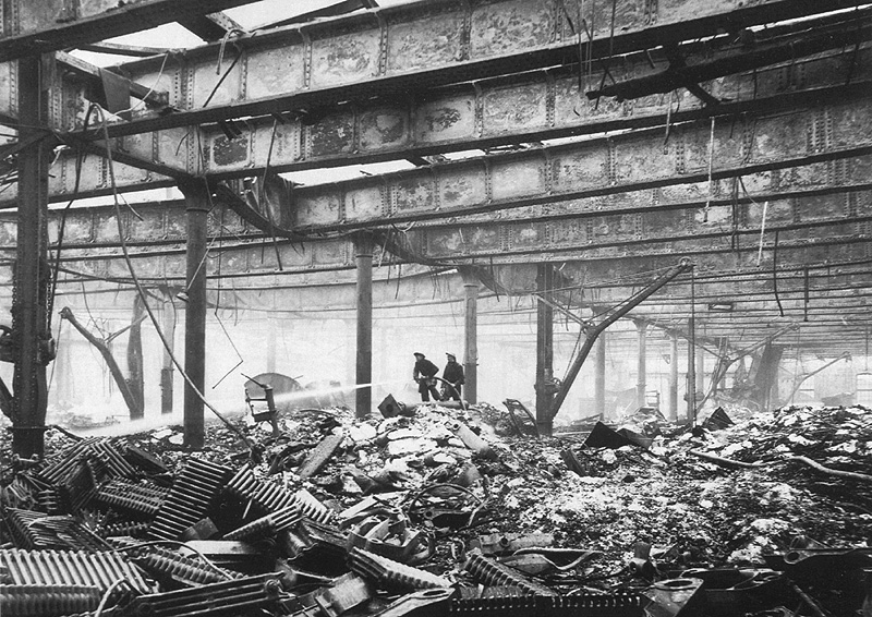 Firemen are seen dampening down the smouldering remains of the warehouse on the 26th October 1940