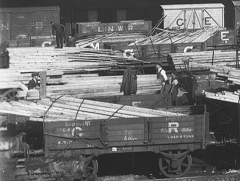 Close up showing the timber planking being transferred to horse-drawn road vehicles for onward distribution