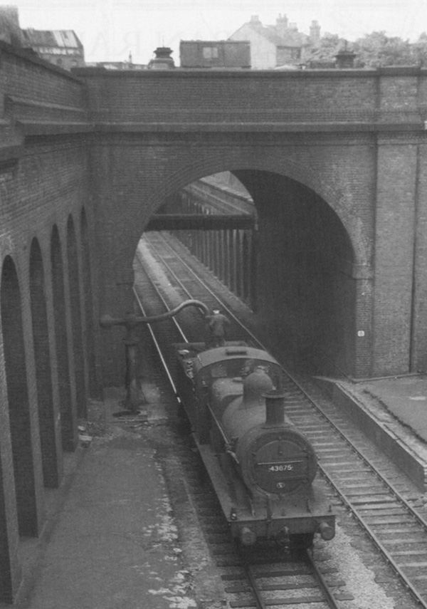 View of ex-LMS 0-6-0 3F No 43675 taking water as it runs tender first to New Street station on 24th May 1953
