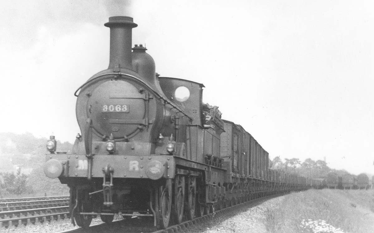 MR 0-6-0 2F No 3063 heads a long goods train of mainly open wagons but with fitted vans immediately behind the tender circa 1913
