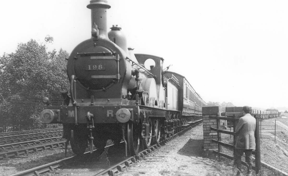 MR 2-4-0 No 198 heads a local train past Kings Norton station's carriage storage and goods sidings