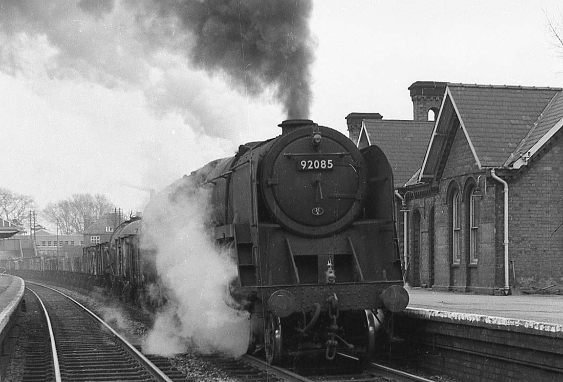 British Railways Standard Class 9F 2-10-0 No 92085 passes through the station on an up Type 8 freight working