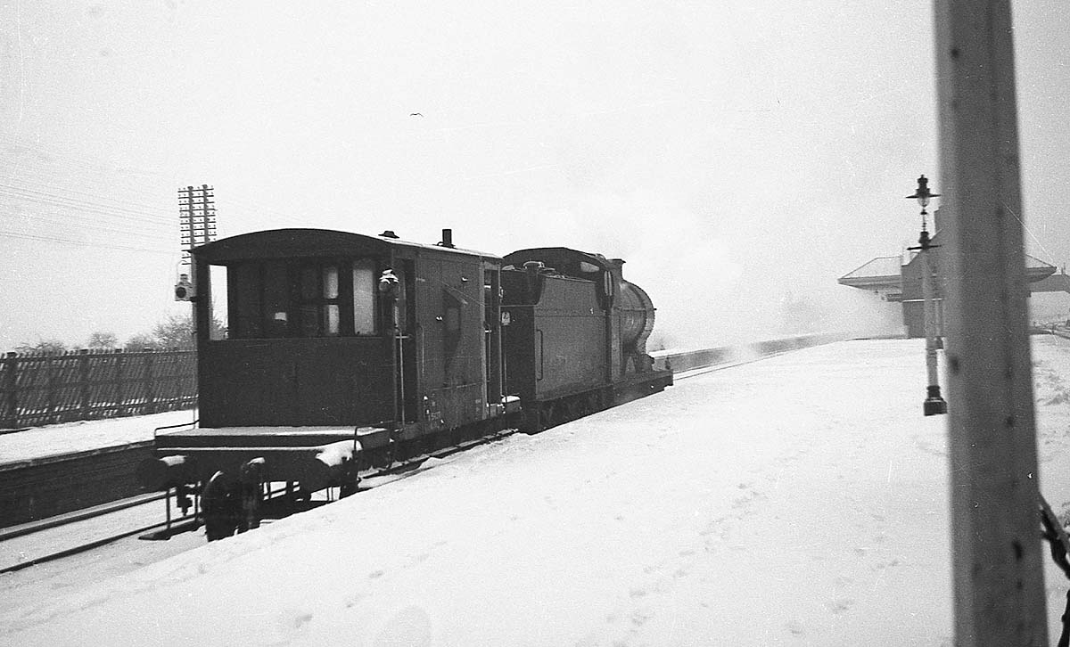 An unidentified ex-LMS 0-6-0 4F locomotive is seen towing a guards or 'brake' van through Kings Norton Station in the winter of 1961