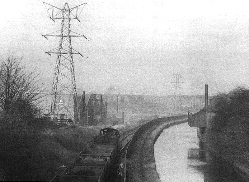 View of an unidentified ex-MR 0-6-0 locomotive at the head of a rake of open wagons as it traverses the canal branch