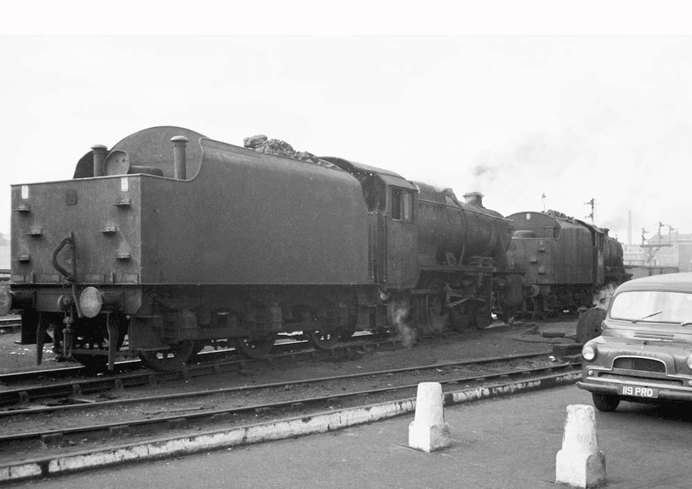 Ex-LMS 8F 2-8-0 No 48336 follows an unidentified class member past Saltley's amenities block and out of the shed