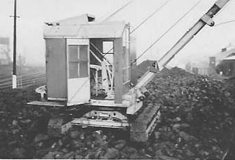A crawler crane is seen loading coal from Saltley shed's coal stack into 'Loco' wagons to be taken to the Coaling Tower