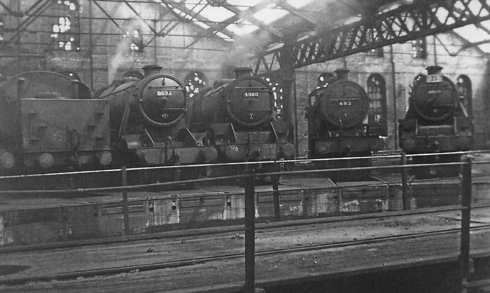 An internal view of one of Saltley's sheds with an array of ex-LMS locomotives in company with an ex-MR locomotive standing on the roads around the turntable