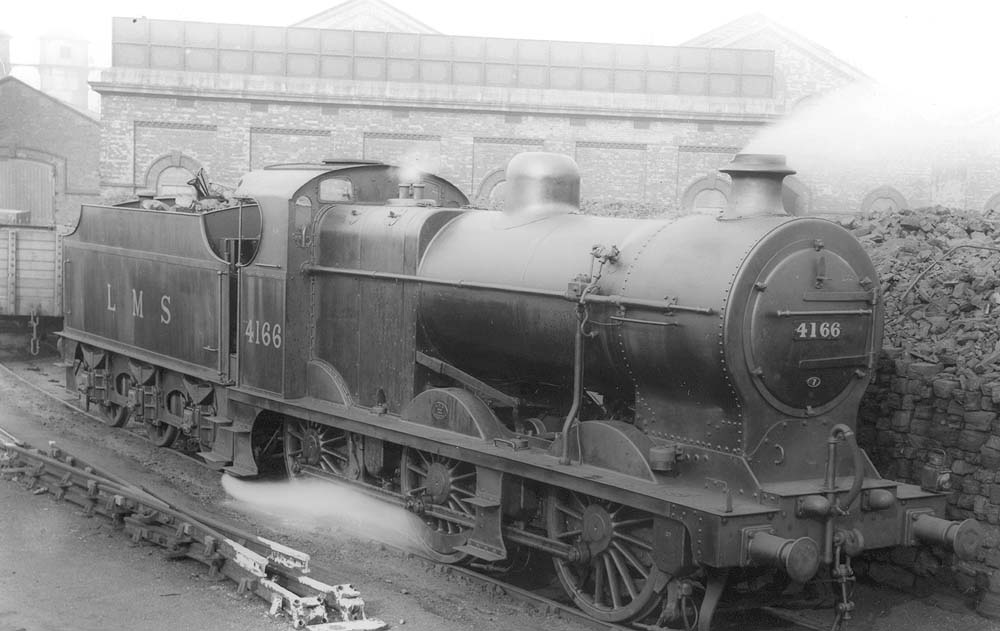 LMS 4F 0-6-0 No 4166 is seen standing near to Saltley's water tank with smoke pouring from the chimney and steam escaping from the safety valves