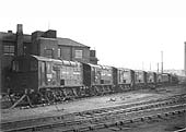 A line of British Railways and LMS 0-6-0 Diesel shunters are seen standing adjacent to the entrance of Saltley shed's No 2 roundhouse