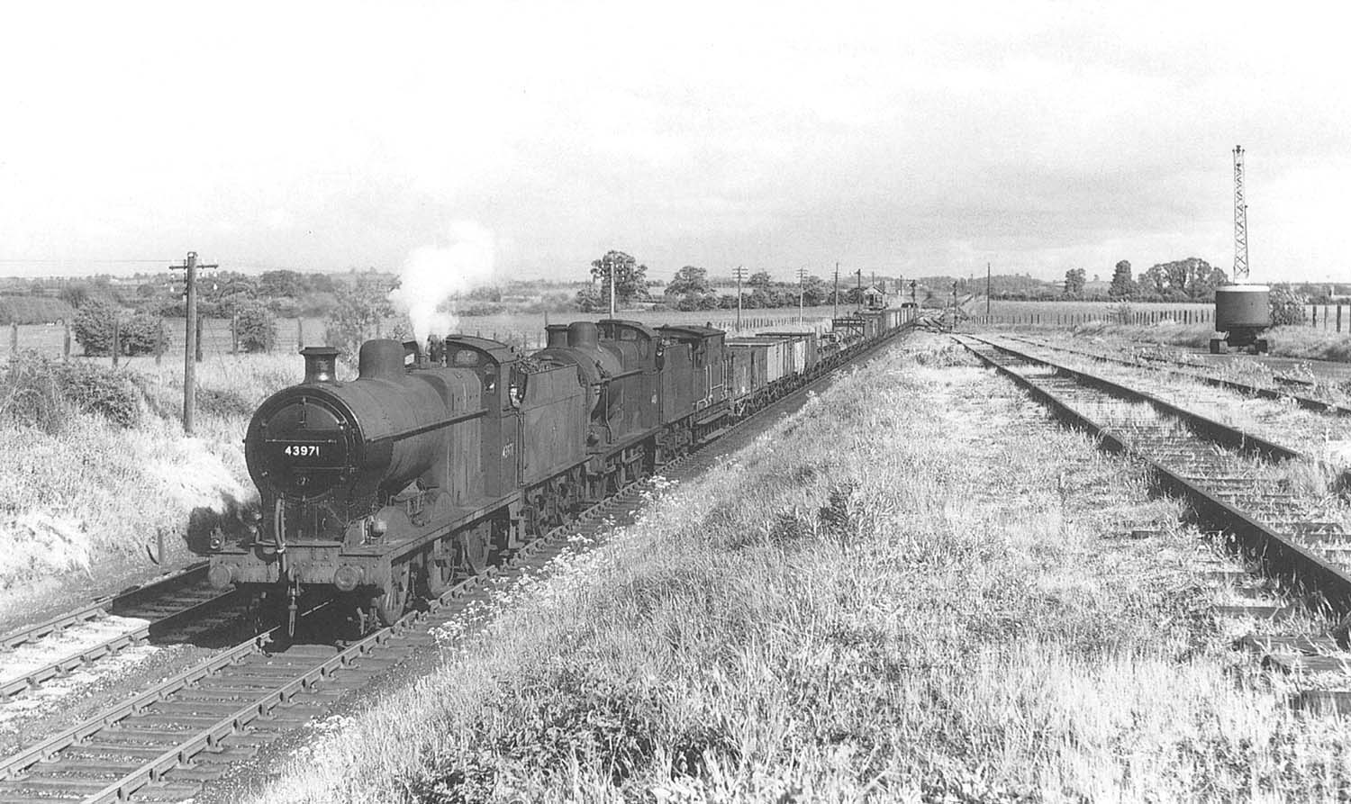 Ex-LMS 4F 0-6-0 No 43971 and classmate No 44219 double head a goods train of minerals wagons past Clifford's Sidings on 16th May 1957