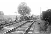 A motorised trolley used by the Permanent Way gang is being manhandled across the running lines at Byfield in 1958