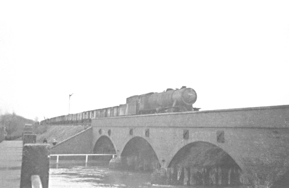An unidentified ex-WD 2-8-0 locomotive is seen crossing the bridge carrying the former SMJ route over the River Avon
