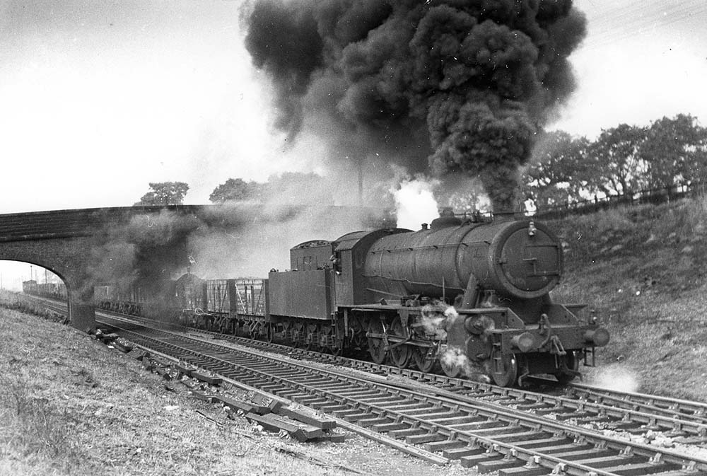 An unidentified ex-WD 2-8-0 Austerity locomotive seen at the head of a long coal train is emitting lots of smoke as it approaches Catesby Tunnel