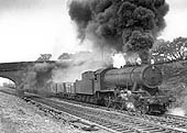 An unidentified ex-WD 2-8-0 Austerity locomotive seen at the head of a long coal train is emitting lots of smoke