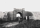 View of a brick arched bridge with curved retaining wing walls which carried the GC line to London over a farm track