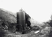 A navvy poses for the camera besides a pumping engine fitted with a vertical boiler at the foot of an embankment