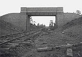A single line of contractor's temporary track passes beneath a brick and girder overbridge near Rainsbrook