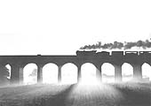 An LNER K3 Class 2-6-0 locomotive is silhouetted against the morning sun whilst crossing the GCR viaduct