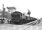British Railways 0-6-0T No 1501 is seen running tender first at the head of a long coal train crossing Wheelwright Lane level crossing